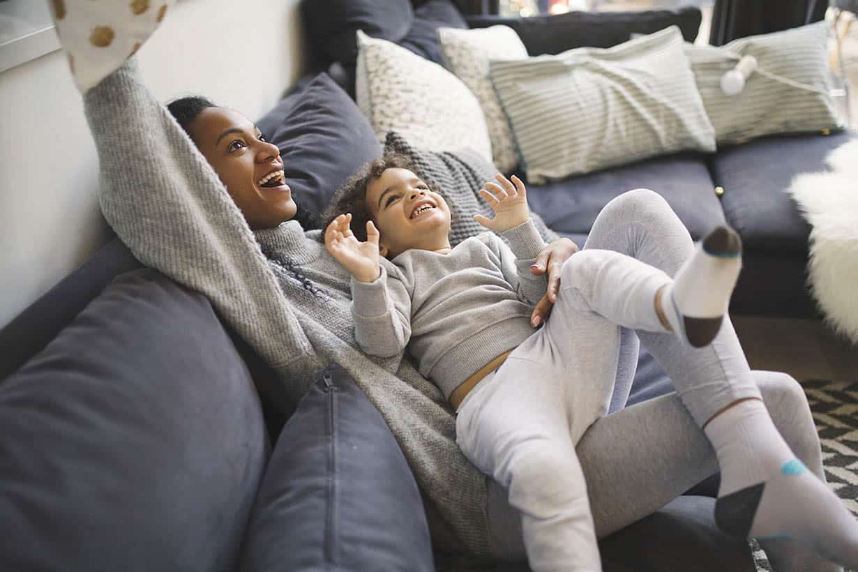 Family time Mother and child laughing and playing on couch in living room